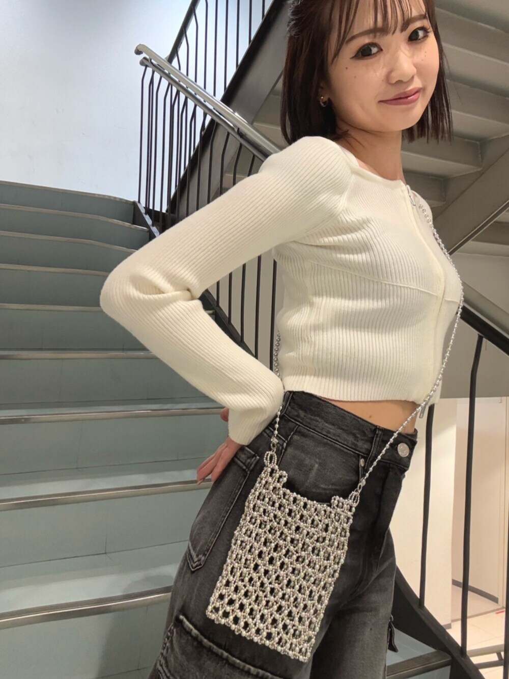 ブラック系のデニムパンツ、ブラック系のブーツ、ホワイト系のニット/セーターを着用したレディースの冬コーディネートの5枚目の写真