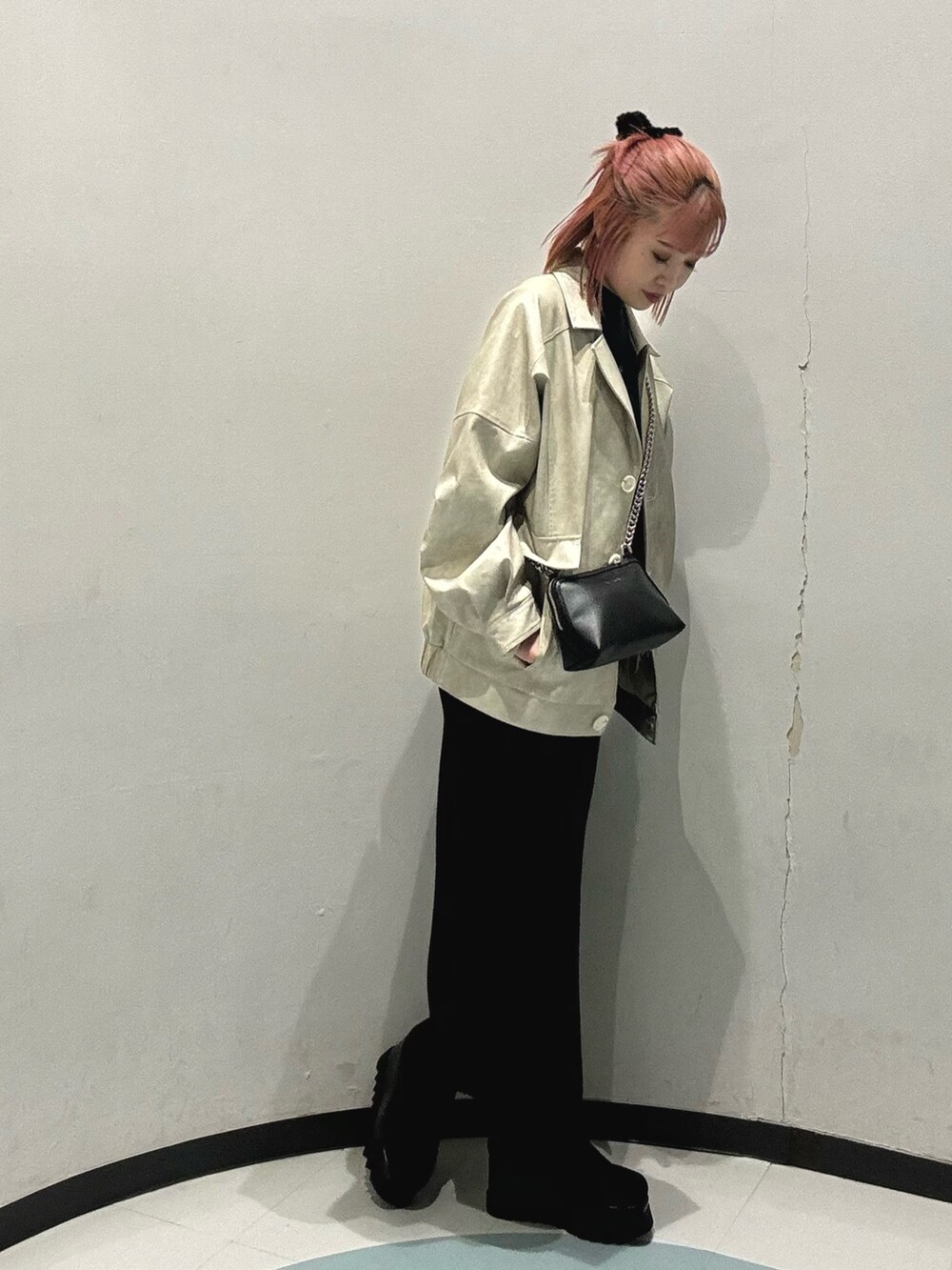 グリーン系のニット/セーター、ホワイト系のブルゾン、ブラック系のスカートを着用したレディースの冬コーディネートの2枚目の写真