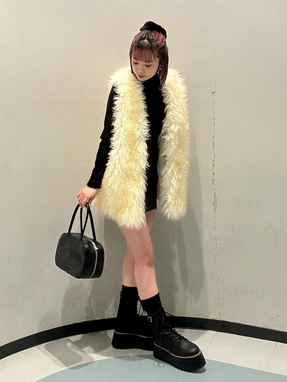 ブラック系のニット/セーター、ホワイト系のベスト、グリーン系のスカートを着用したレディースの秋コーディネートの2枚目の写真