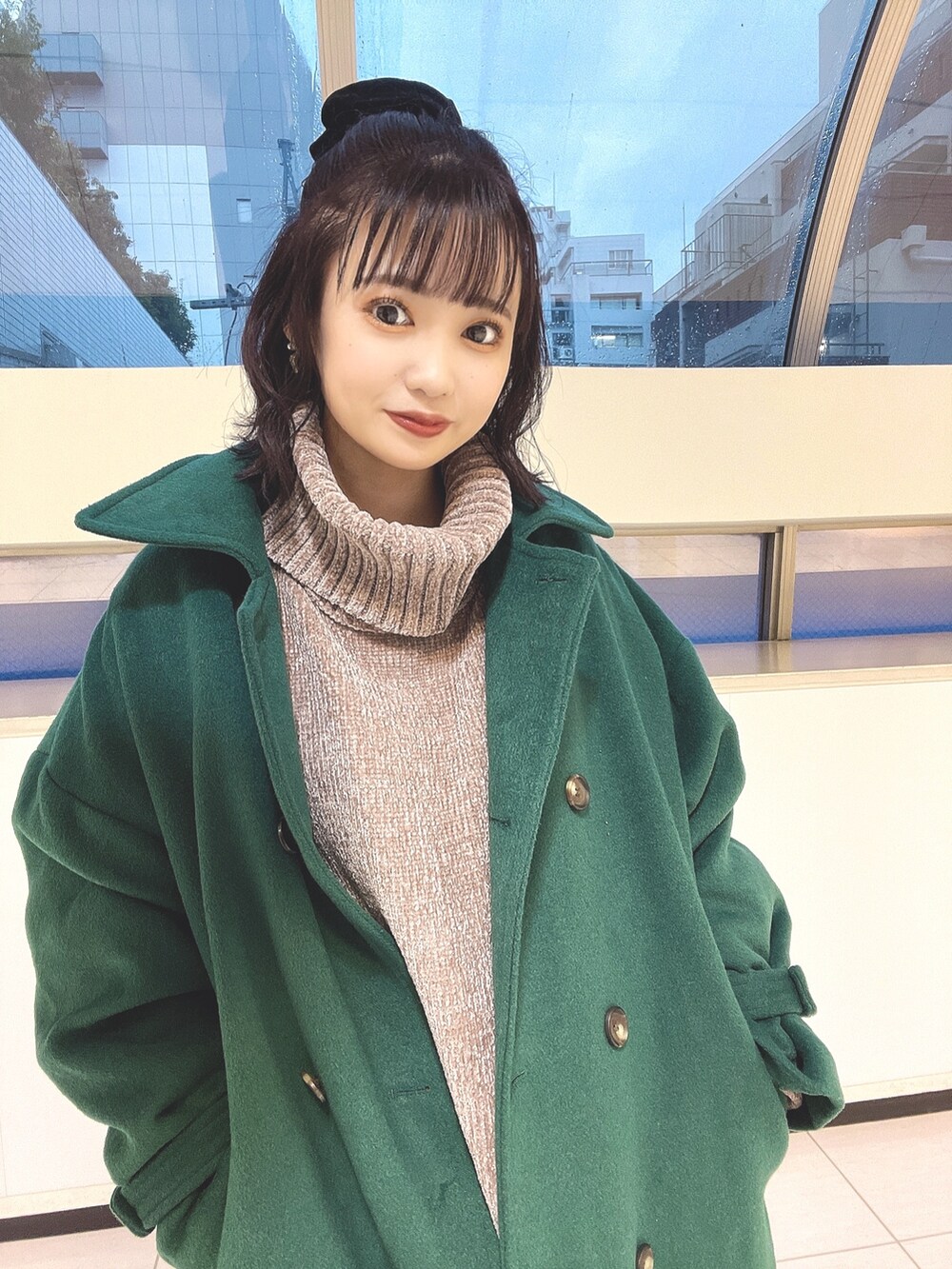 グリーン系のステンカラーコート、ブラウン系のワンピースを着用したレディースの秋コーディネートの3枚目の写真