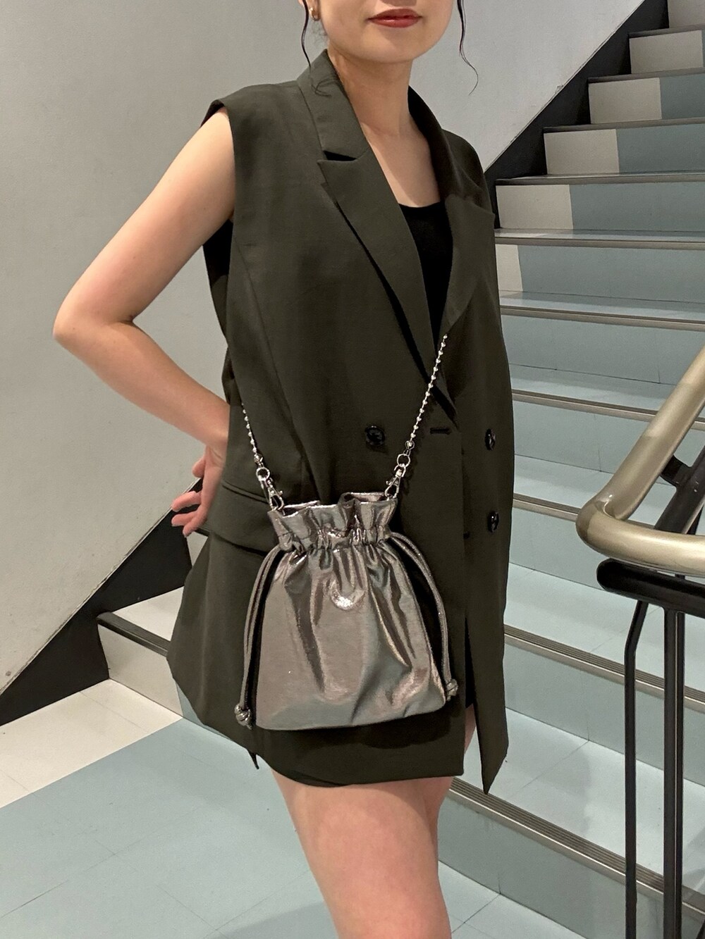 グレー系のベスト、グレー系のスカート、グレー系のショルダーバッグを着用したレディースの春コーディネートの4枚目の写真