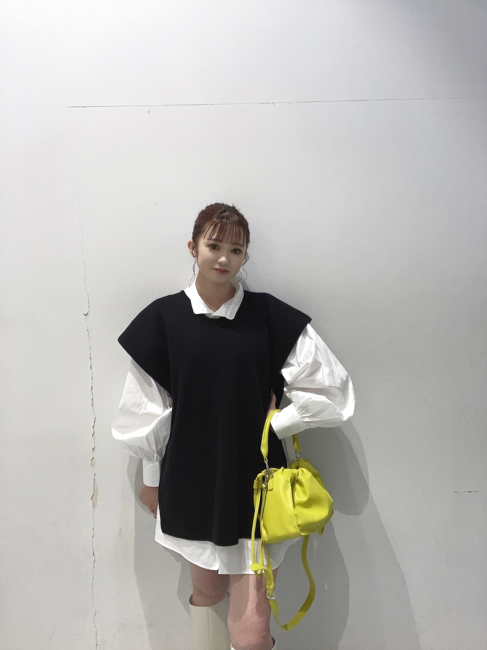 イエロー系のハンドバッグ、ブラック系のワンピースを着用したレディースの夏コーディネートの2枚目の写真