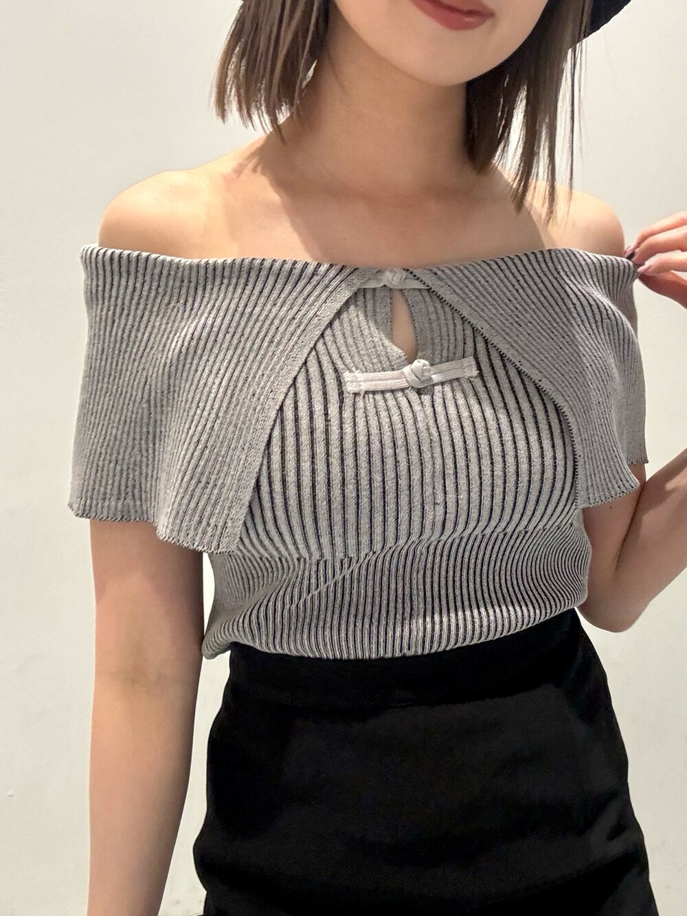 グレー系のニット/セーター、ブラック系のスカート、オレンジ系のショルダーバッグを着用したレディースの春コーディネートの4枚目の写真