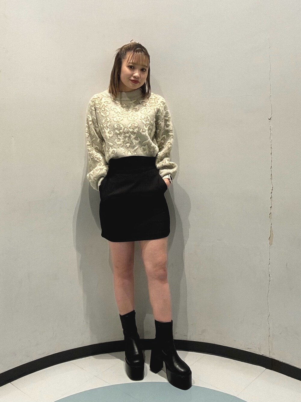 グレー系のダウンジャケット/コート、ホワイト系のニット/セーター、ブラック系のショルダーバッグを着用したレディースの秋コーディネートの2枚目の写真