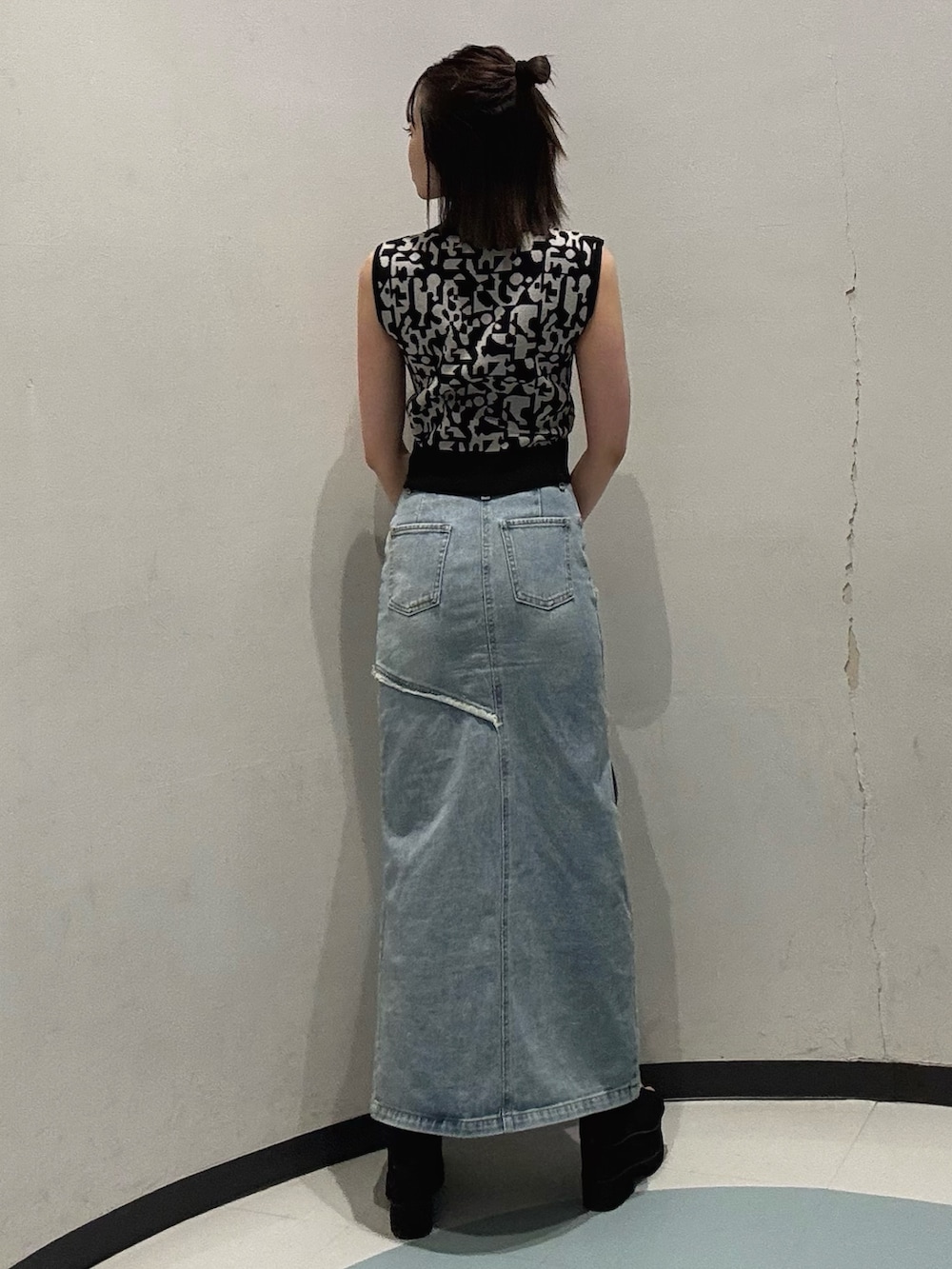 ブラック系のニット/セーター、ブルー系のデニムスカート、ブラック系のサンダルを着用したレディースの夏コーディネートの3枚目の写真