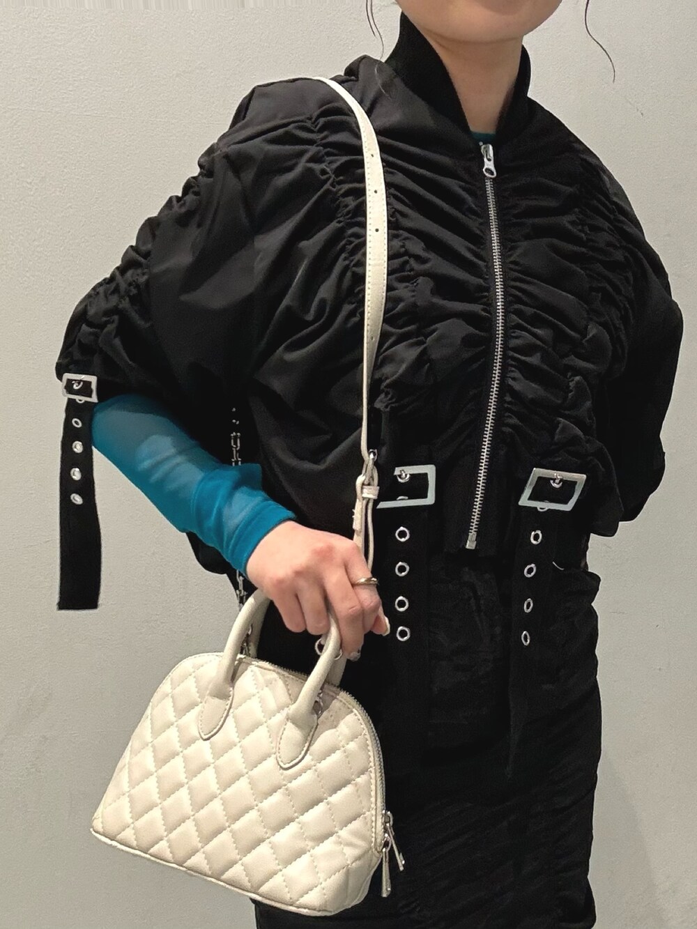 ブラック系のスカート、ホワイト系のハンドバッグ、ブラック系のブルゾンを着用したレディースの春コーディネートの6枚目の写真