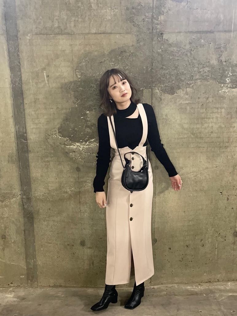 ブラック系のニット/セーター、ホワイト系のワンピース、ベージュ系のトレンチコートを着用したレディースの秋コーディネートの3枚目の写真