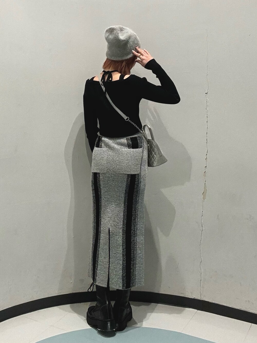 ブラック系のブーツ、シルバー系のハンドバッグ、グレー系のスカートを着用したレディースの冬コーディネートの3枚目の写真