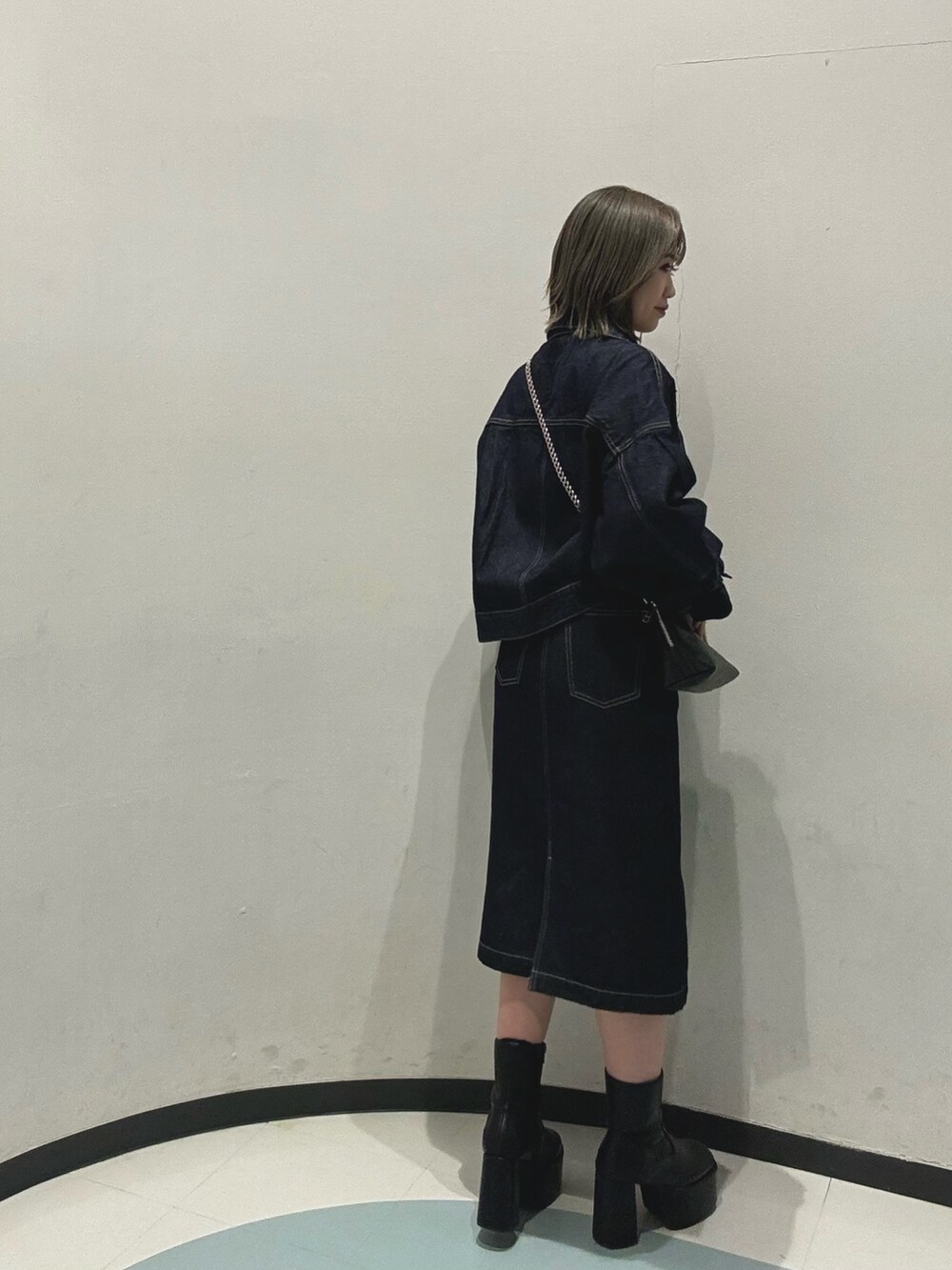 ブラック系のハンドバッグ、ブルー系のデニムジャケット、ブルー系のワンピースを着用したレディースの冬コーディネートの3枚目の写真