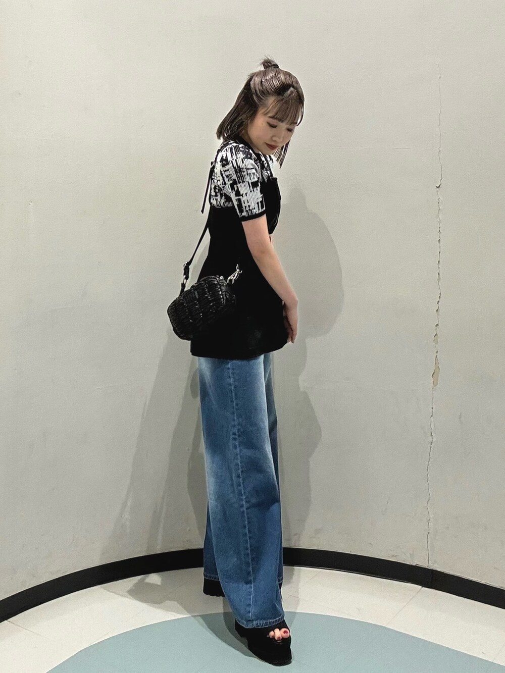 ブラック系のショルダーバッグ、ブラック系のシャツ/ブラウス、ブルー系のデニムパンツを着用したレディースの春コーディネートの2枚目の写真