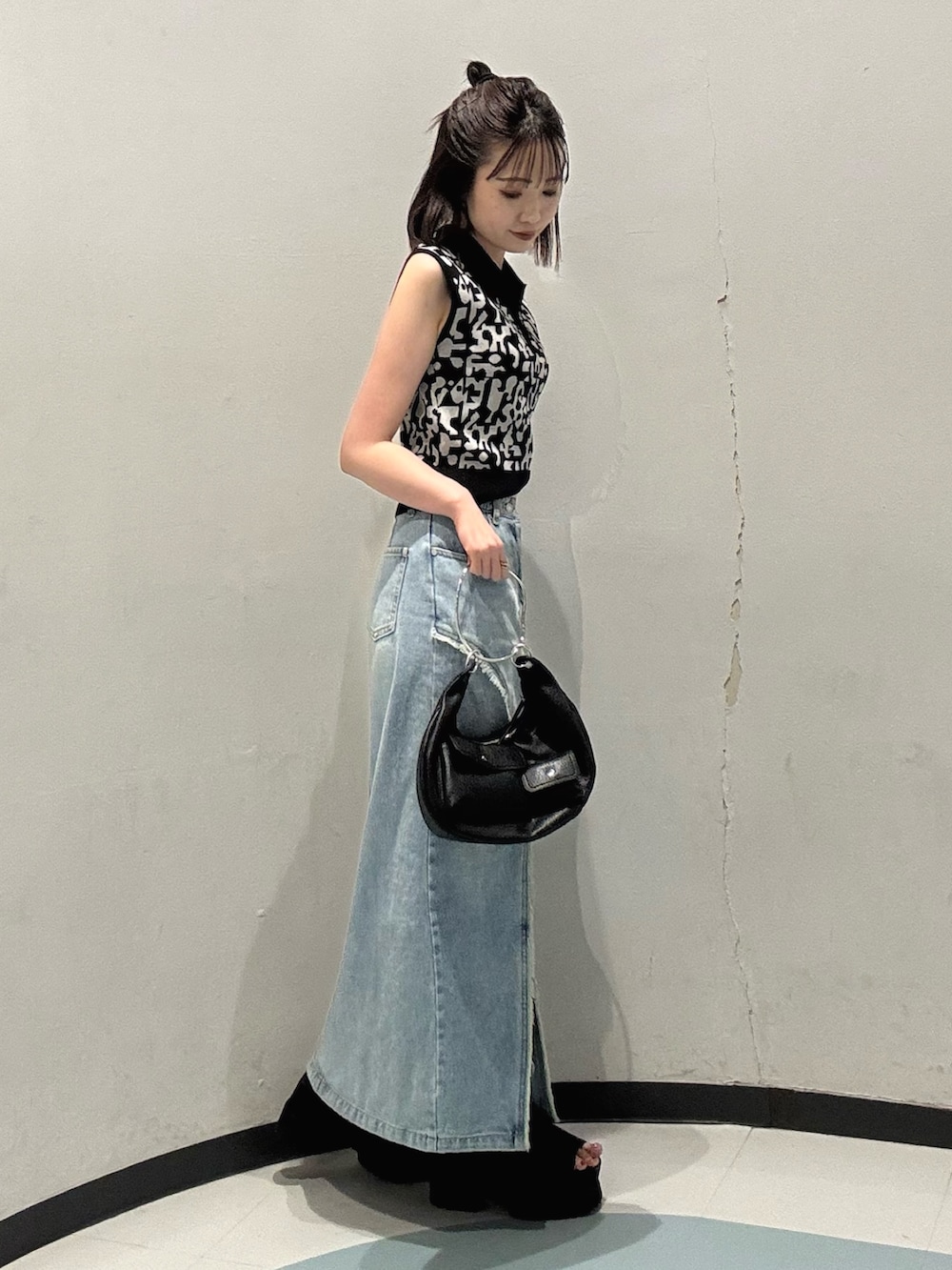 ブラック系のニット/セーター、ブルー系のデニムスカート、ブラック系のサンダルを着用したレディースの夏コーディネートの2枚目の写真