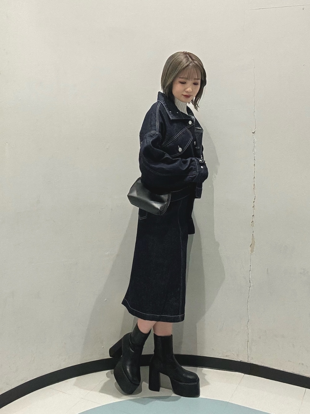 ブラック系のハンドバッグ、ブルー系のデニムジャケット、ブルー系のワンピースを着用したレディースの冬コーディネートの2枚目の写真