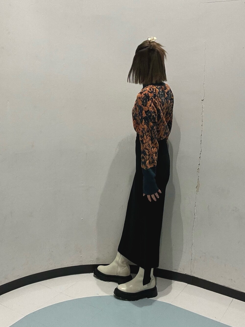 ブラック系のスカート、グリーン系のニット/セーター、ブラック系のハンドバッグを着用したレディースの冬コーディネートの3枚目の写真