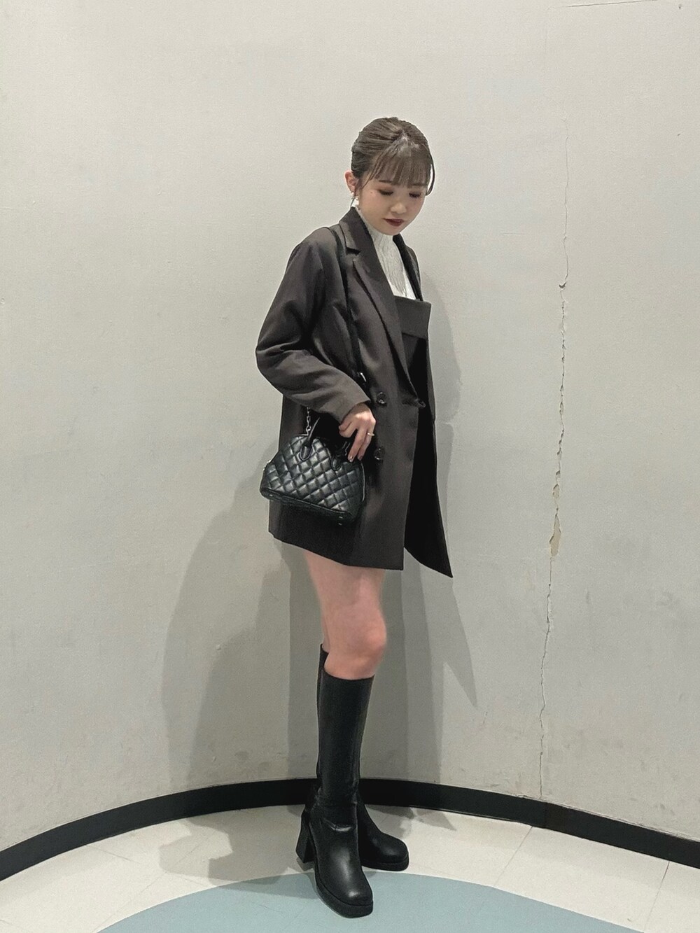 グレー系のテーラードジャケット、ブラック系のハンドバッグ、グレー系のシャツ/ブラウスを着用したレディースの冬コーディネートの2枚目の写真