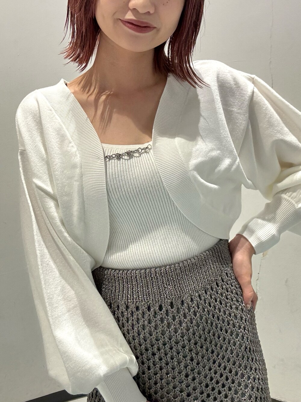 ホワイト系のカーディガン/ボレロ、グレー系のスカート、ブラウン系のブーツを着用したレディースの秋コーディネートの4枚目の写真