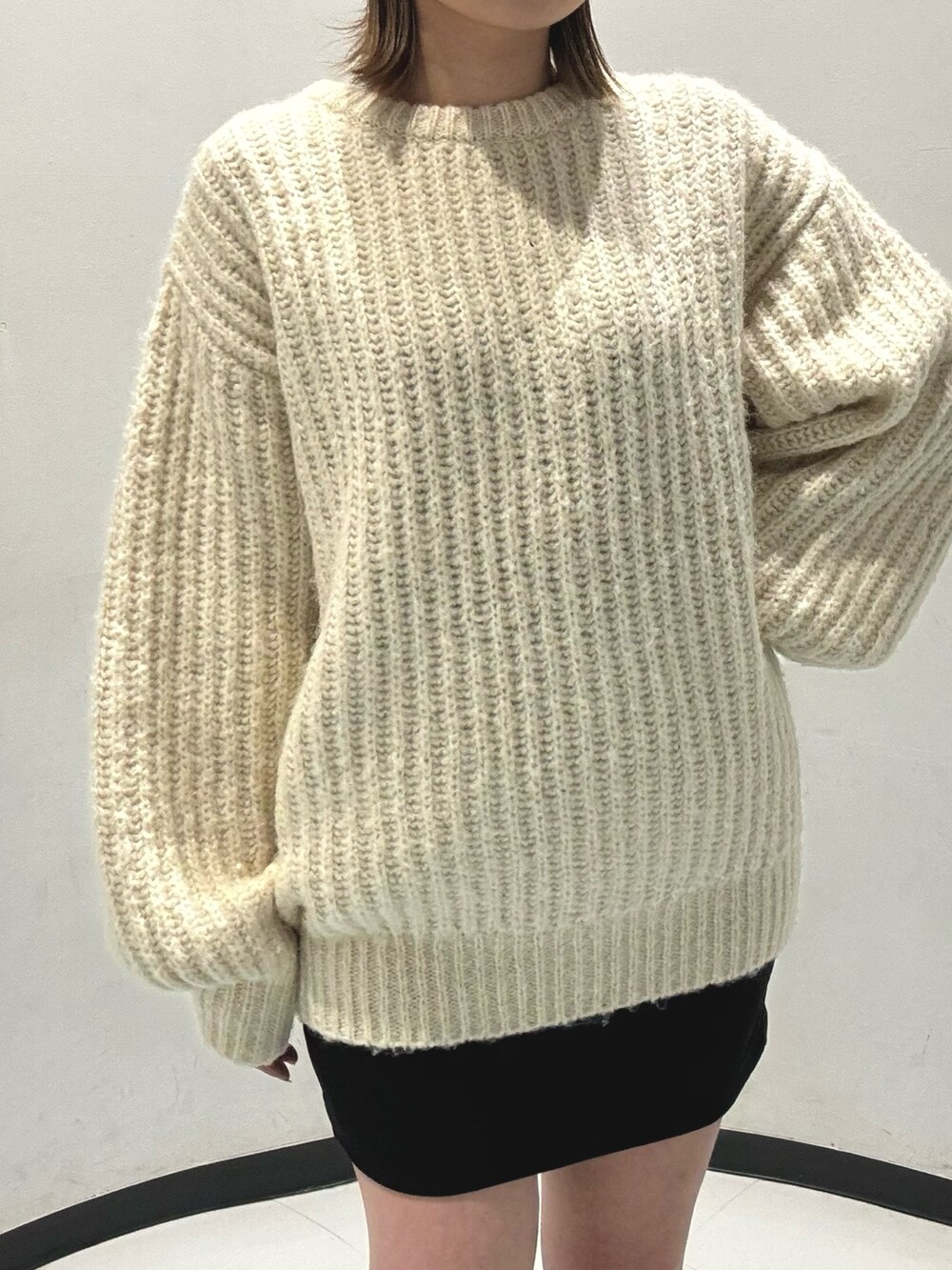 ブラック系のスカート、ホワイト系のニット/セーター、グリーン系のブーツを着用したレディースの秋コーディネートの6枚目の写真