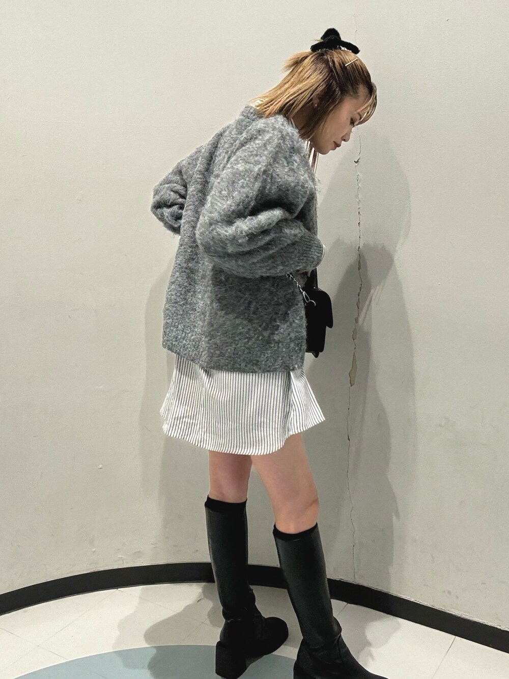 ブラック系のハンドバッグ、グレー系のニット/セーター、ブラック系のブーツを着用したレディースの秋コーディネートの3枚目の写真