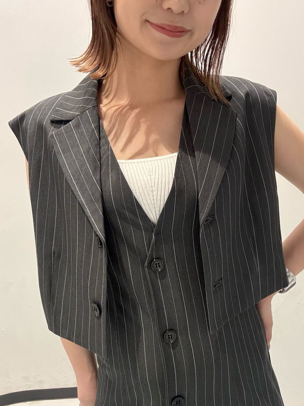 ブラック系のショルダーバッグ、ブラック系のサンダル、グレー系のジャンパースカートを着用したレディースの夏コーディネートの5枚目の写真