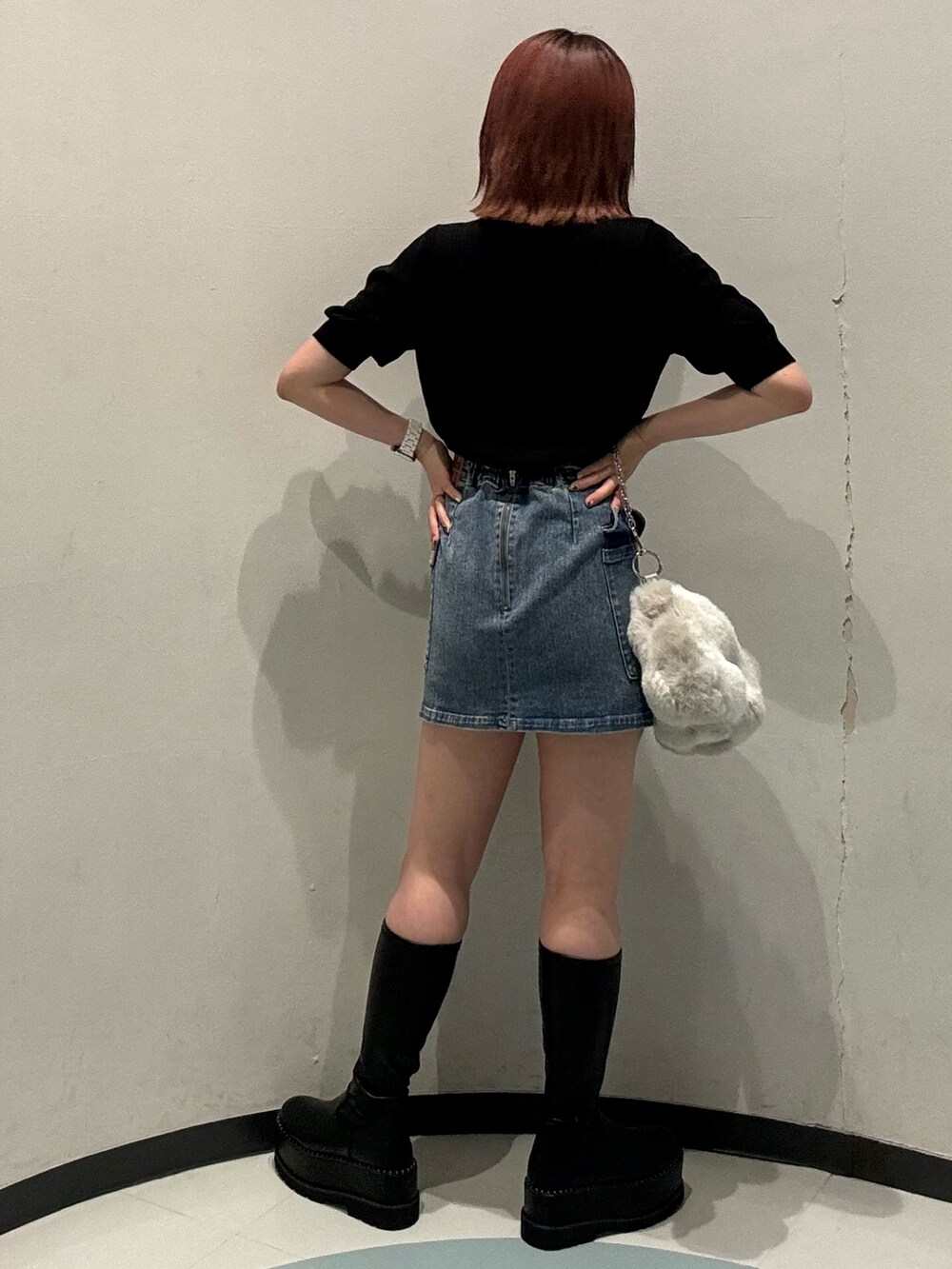 ブラック系のニット/セーター、ブルー系のスカート、ブラック系のブーツを着用したレディースの夏コーディネートの3枚目の写真