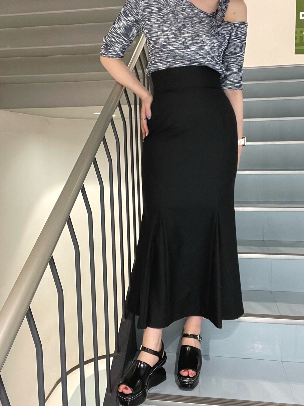 ブラック系のスカート、ブルー系のニット/セーター、ブラック系のサンダルを着用したレディースの春コーディネートの6枚目の写真