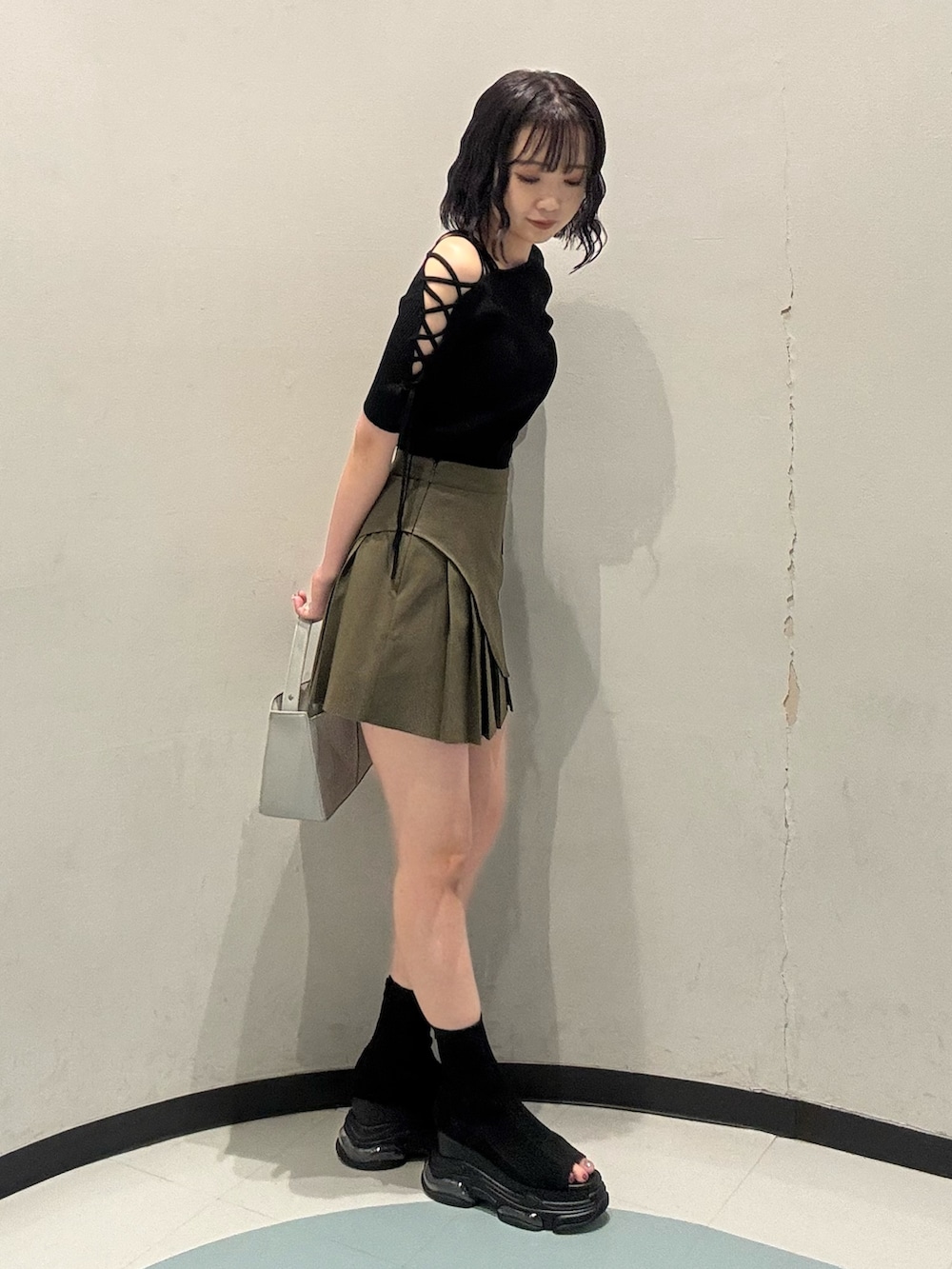 シルバー系のハンドバッグ、ブラック系のサンダル、ブラック系のニット/セーターを着用したレディースの夏コーディネートの2枚目の写真