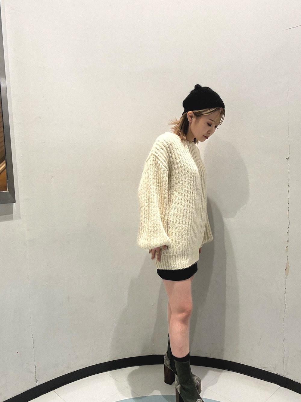 ブラック系のスカート、ホワイト系のニット/セーター、グリーン系のブーツを着用したレディースの秋コーディネートの3枚目の写真