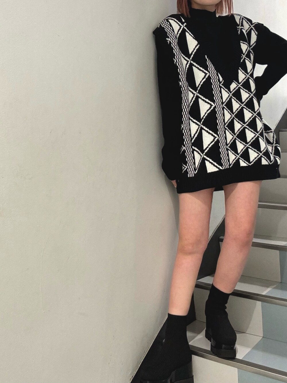 ブラック系のブーツ、ホワイト系のハンドバッグ、その他のベストを着用したレディースの冬コーディネートの5枚目の写真