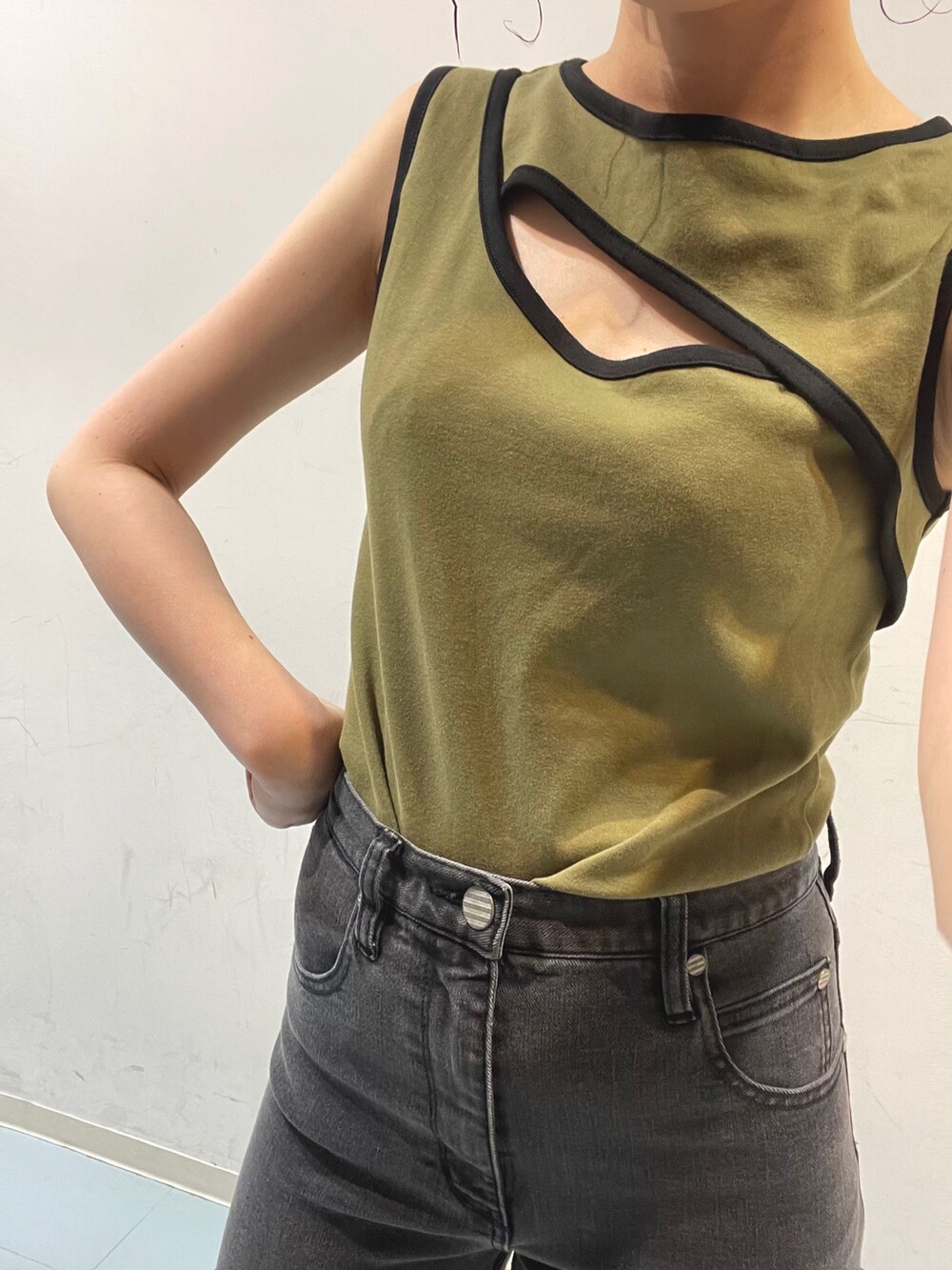 ブラック系のショルダーバッグ、グリーン系のタンクトップ、グレー系のデニムパンツを着用したレディースの夏コーディネートの6枚目の写真