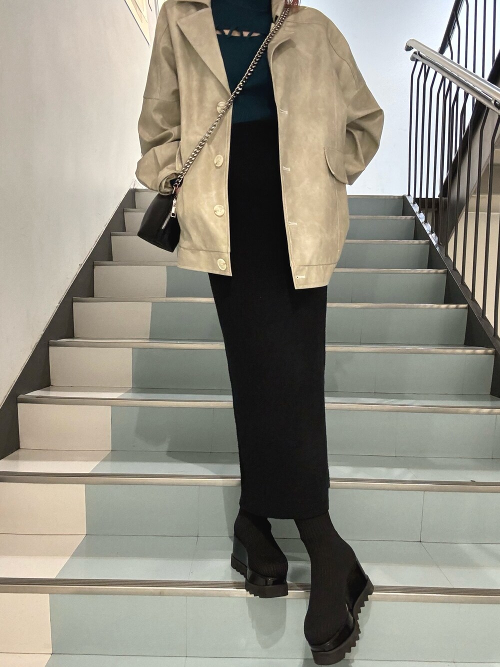 グリーン系のニット/セーター、ホワイト系のブルゾン、ブラック系のスカートを着用したレディースの冬コーディネートの6枚目の写真