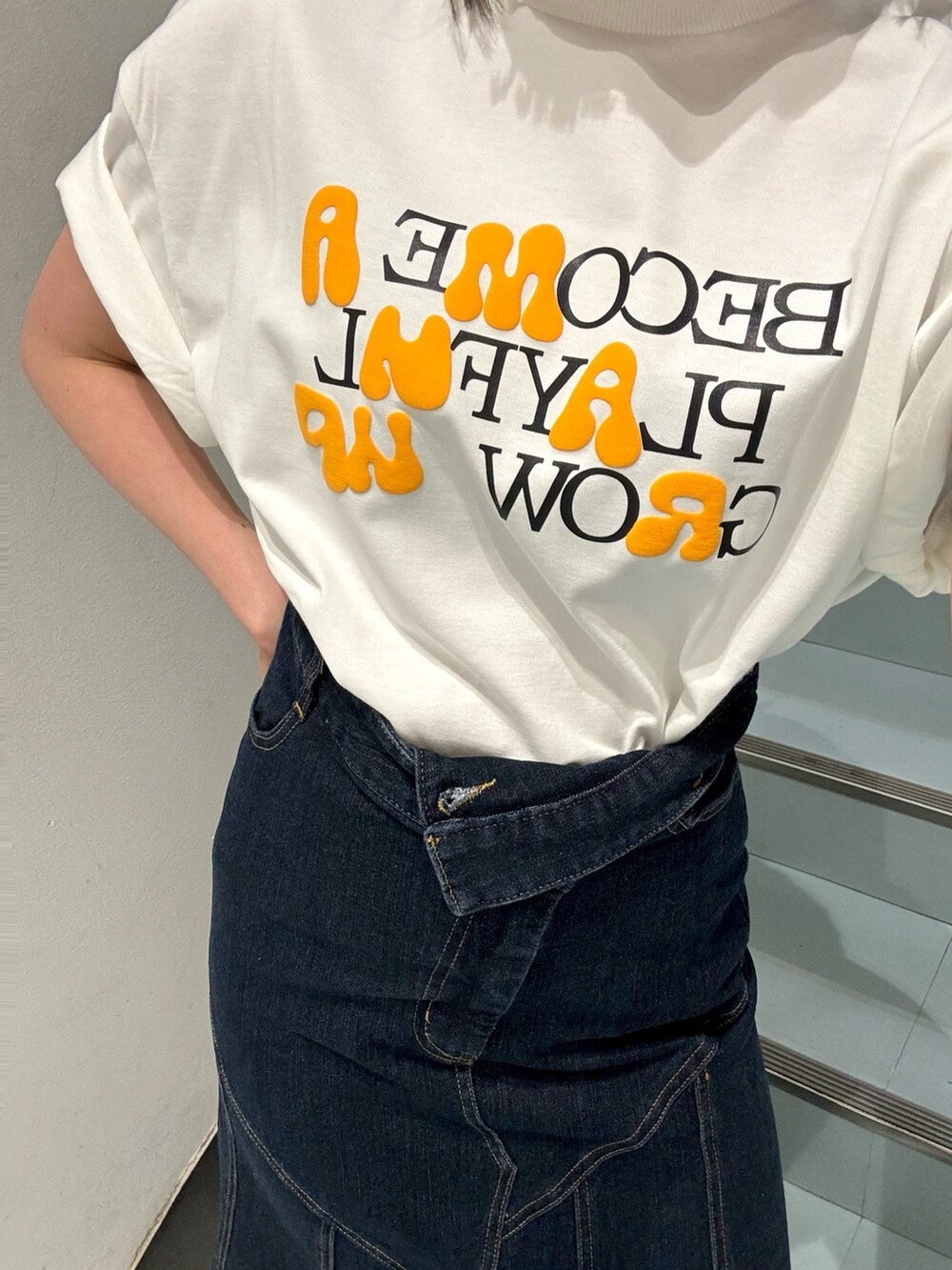 ブルー系のデニムスカート、ホワイト系のTシャツ/カットソー、シルバー系のサンダルを着用したレディースの春コーディネートの6枚目の写真