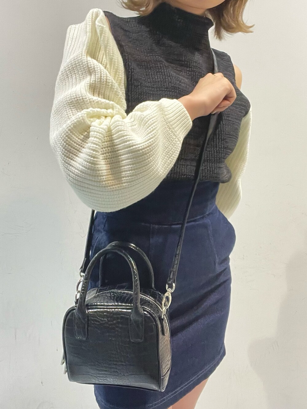 ブラック系のボストンバッグ、ブラック系のニット/セーター、ブラック系のブーツを着用したレディースの秋コーディネートの3枚目の写真