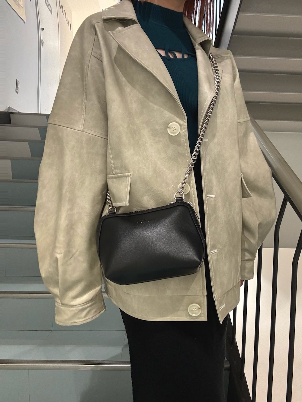 グリーン系のニット/セーター、ホワイト系のブルゾン、ブラック系のスカートを着用したレディースの冬コーディネートの7枚目の写真