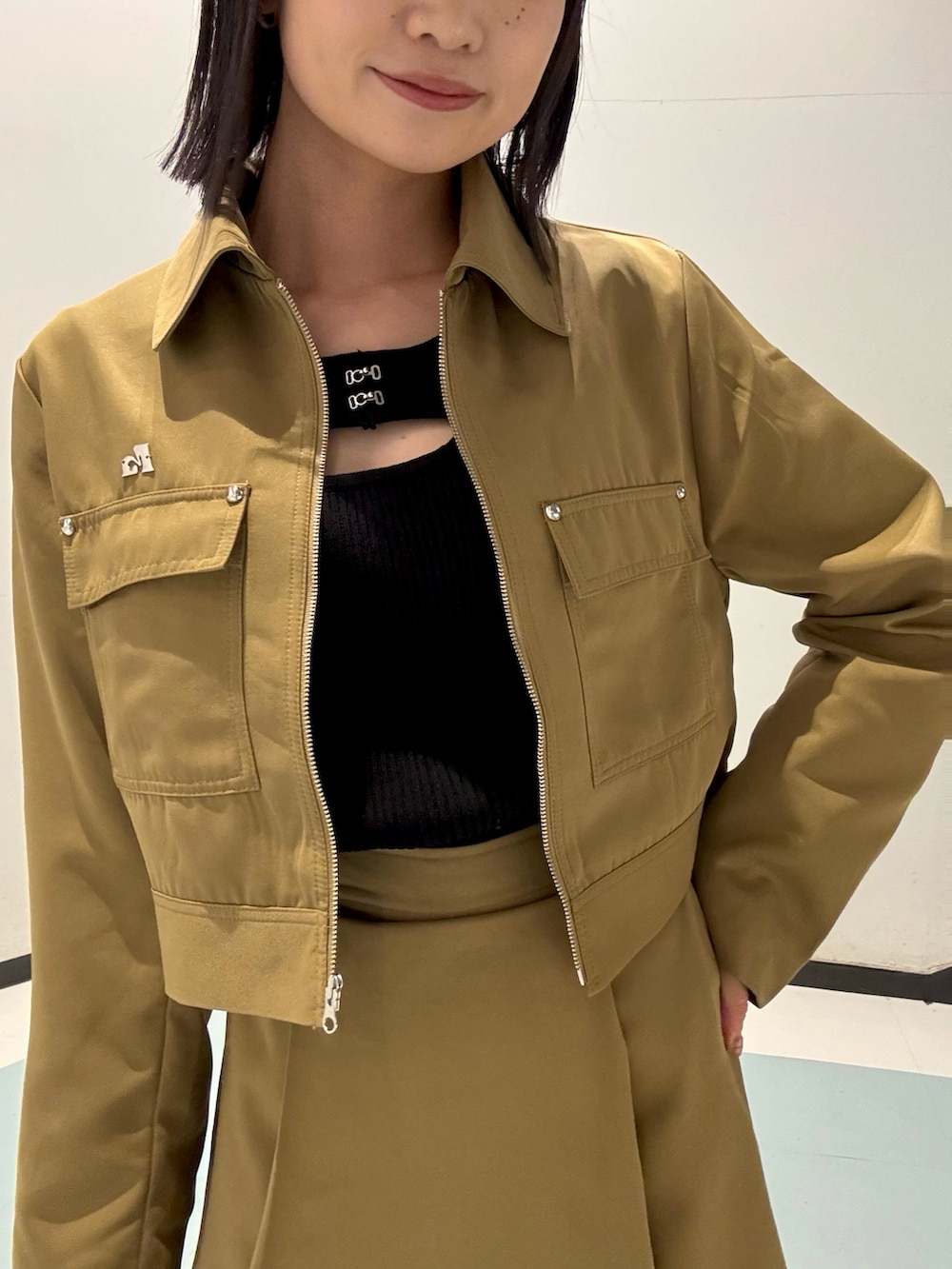 ブラック系のショルダーバッグ、ベージュ系のスカート、ベージュ系のブルゾンを着用したレディースの春コーディネートの4枚目の写真