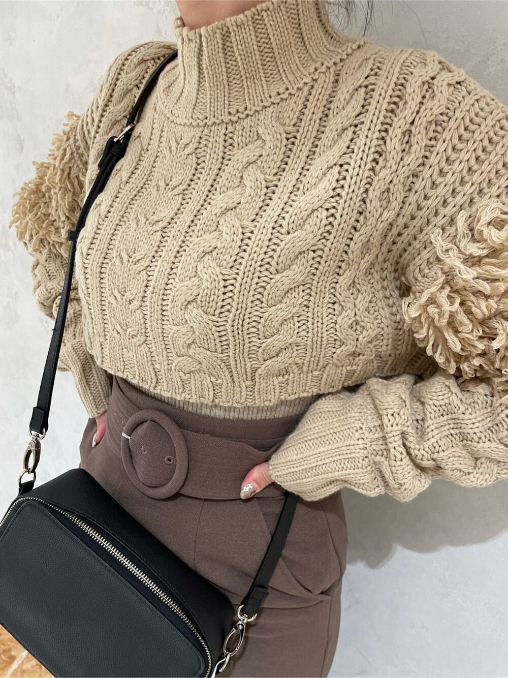 ベージュ系のスカート、ブラック系のショルダーバッグ、ブラック系のブーツを着用したレディースの秋コーディネートの3枚目の写真