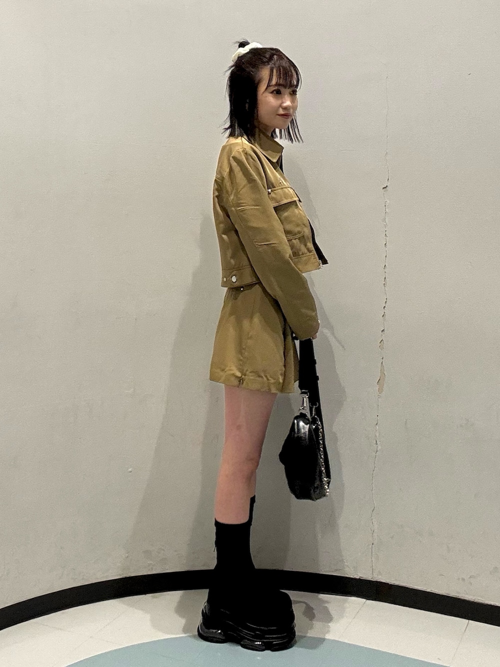 ブラック系のショルダーバッグ、ベージュ系のスカート、ベージュ系のブルゾンを着用したレディースの春コーディネートの2枚目の写真