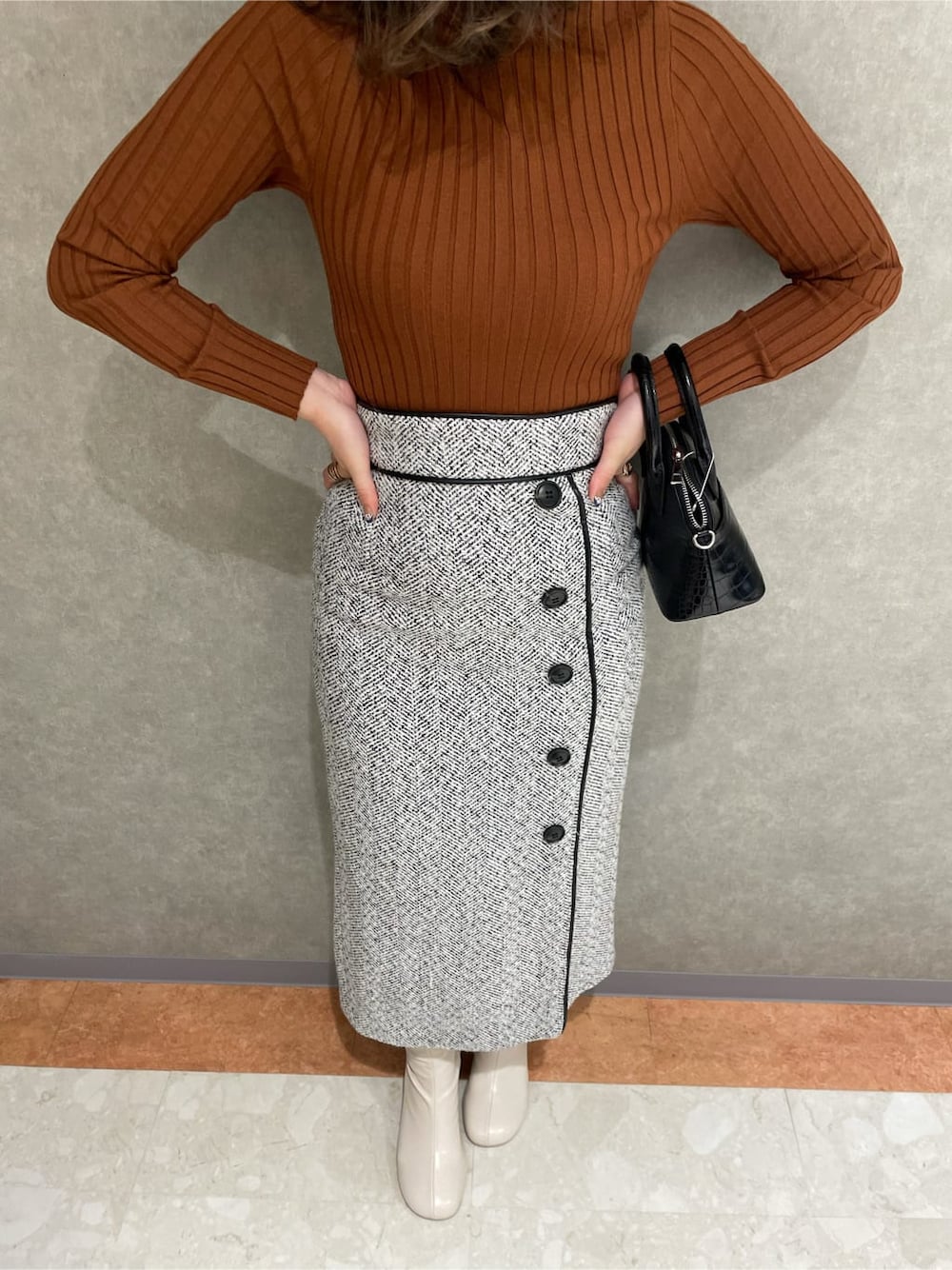 ホワイト系のブーツ、ブラック系のハンドバッグ、ホワイト系のスカートを着用したレディースの秋コーディネートの4枚目の写真