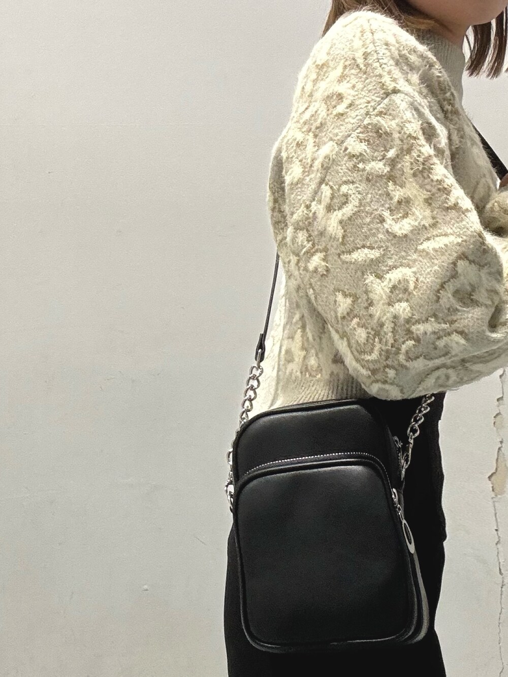 グレー系のダウンジャケット/コート、ホワイト系のニット/セーター、ブラック系のショルダーバッグを着用したレディースの秋コーディネートの6枚目の写真