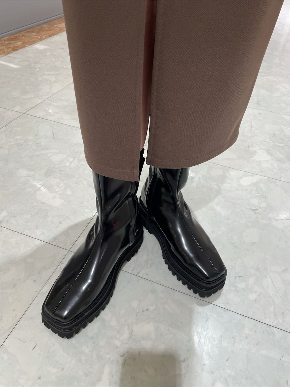 ベージュ系のスカート、ブラック系のショルダーバッグ、ブラック系のブーツを着用したレディースの秋コーディネートの5枚目の写真