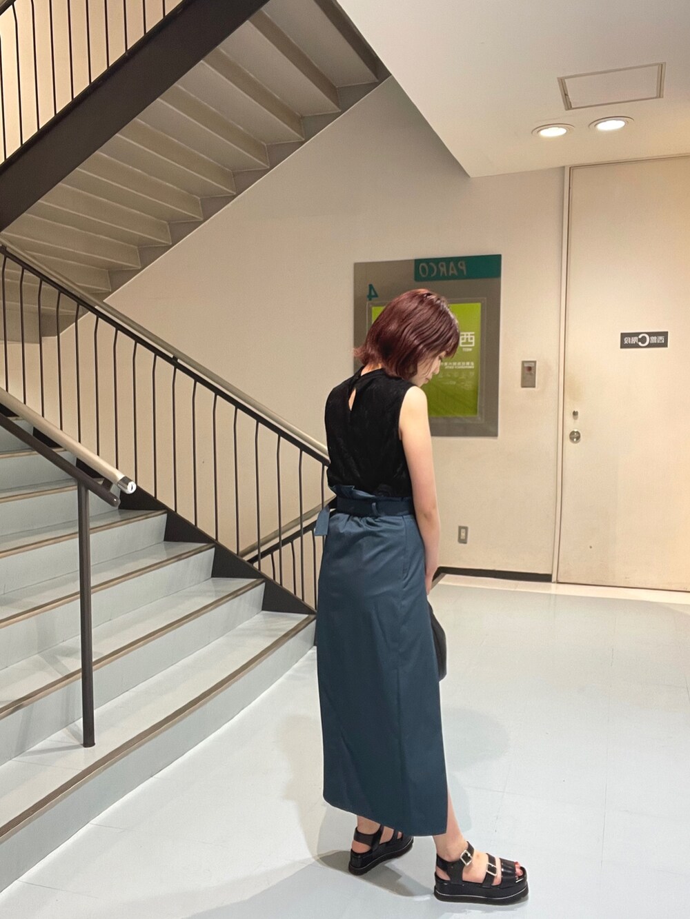 ブラック系のハンドバッグ、ブルー系のスカート、ブラック系のシャツ/ブラウスを着用したレディースの夏コーディネートの3枚目の写真