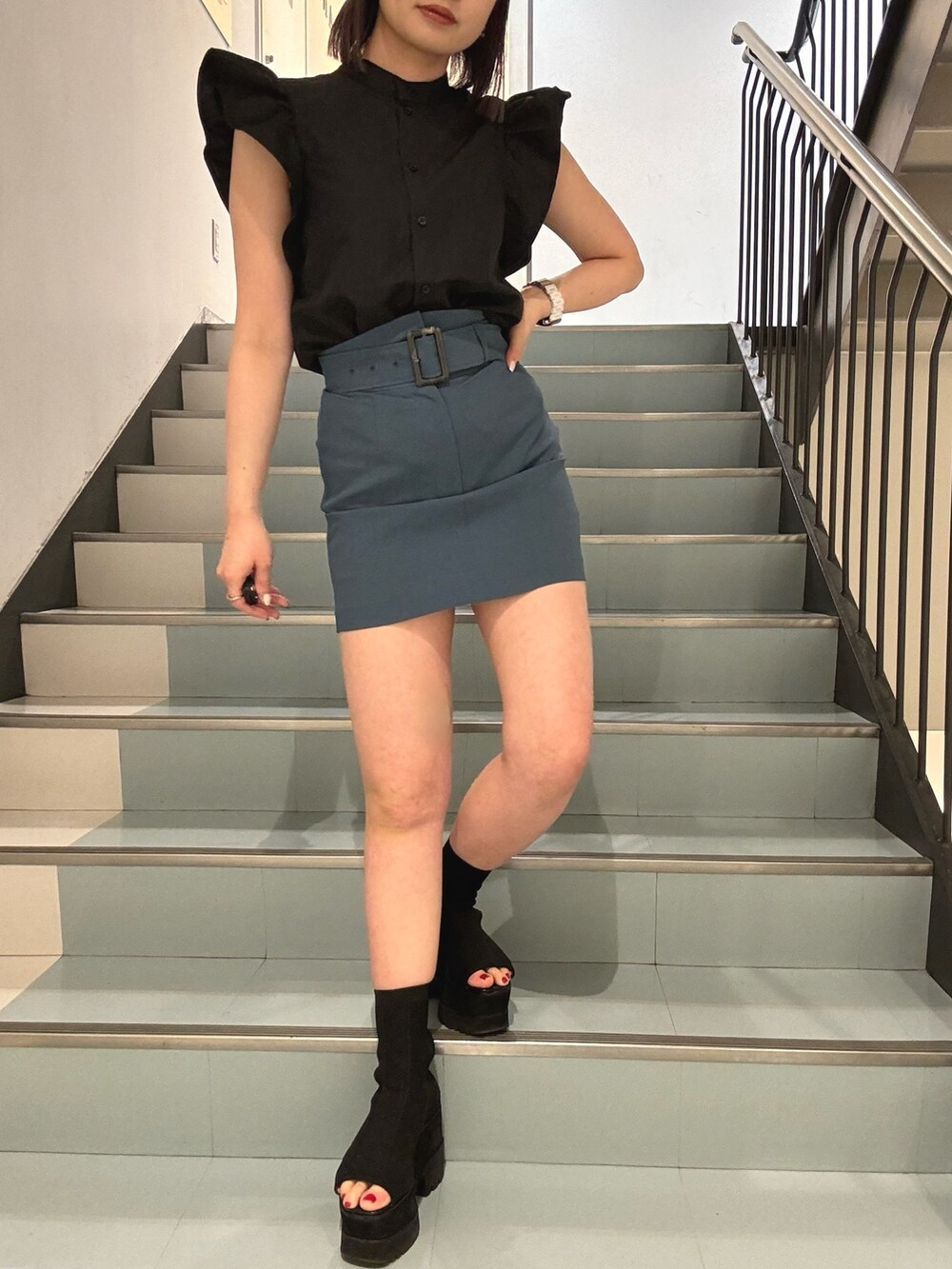 ブラック系のシャツ/ブラウス、ブルー系のスカート、ブラック系のブーツを着用したレディースの春コーディネートの5枚目の写真