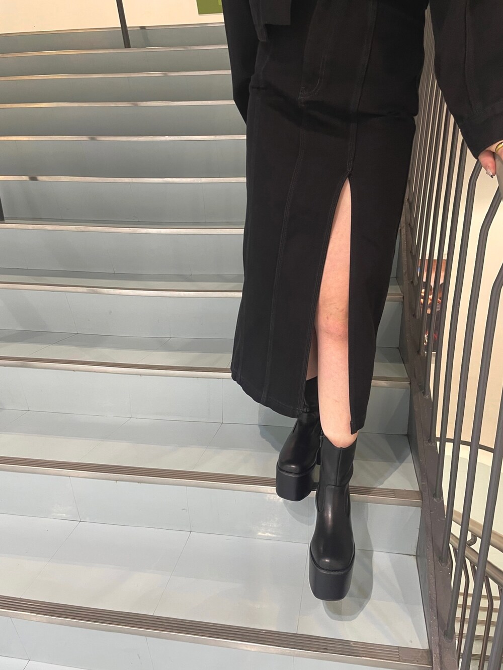 ブラック系のスカート、ブラック系のブーツ、グリーン系のニット/セーターを着用したレディースの夏コーディネートの7枚目の写真