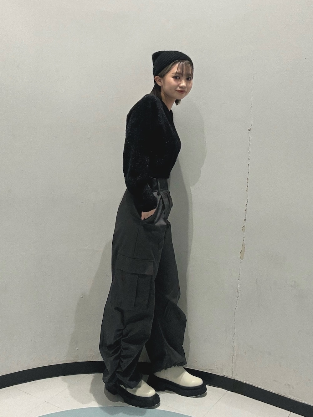 ホワイト系のブーツ、ブラック系のニット/セーター、グレー系のカーゴパンツを着用したレディースの冬コーディネートの2枚目の写真