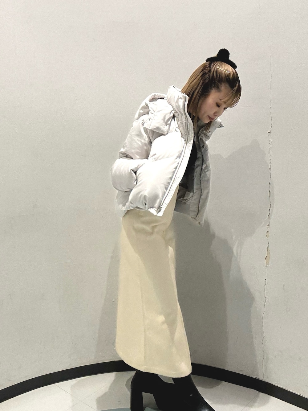 グレー系のダウンジャケット/コート、ホワイト系のニット/セーター、ブラック系のスカートを着用したレディースの秋コーディネートの3枚目の写真