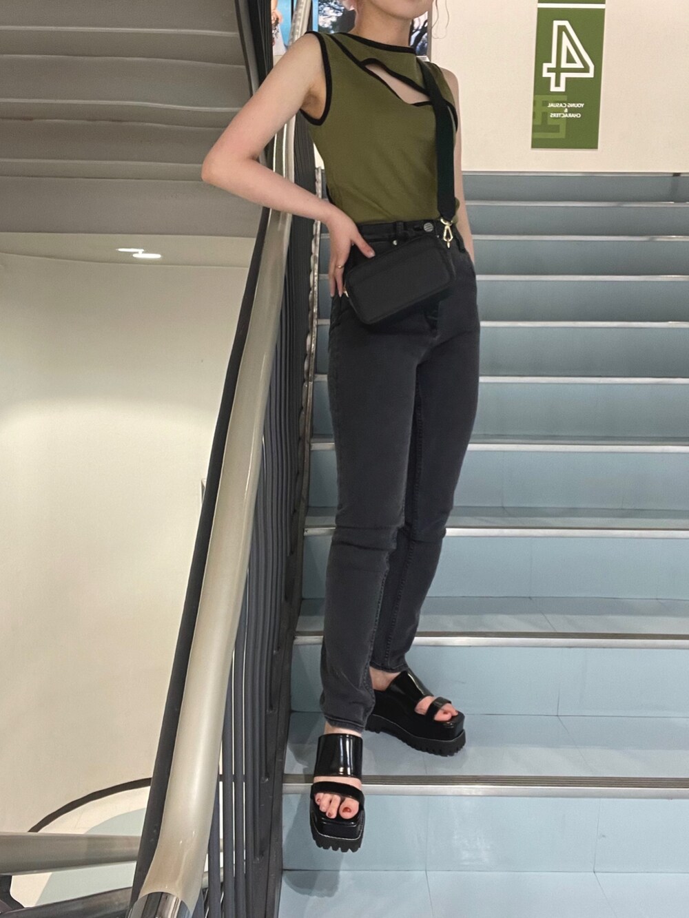 ブラック系のショルダーバッグ、グリーン系のタンクトップ、グレー系のデニムパンツを着用したレディースの夏コーディネートの4枚目の写真