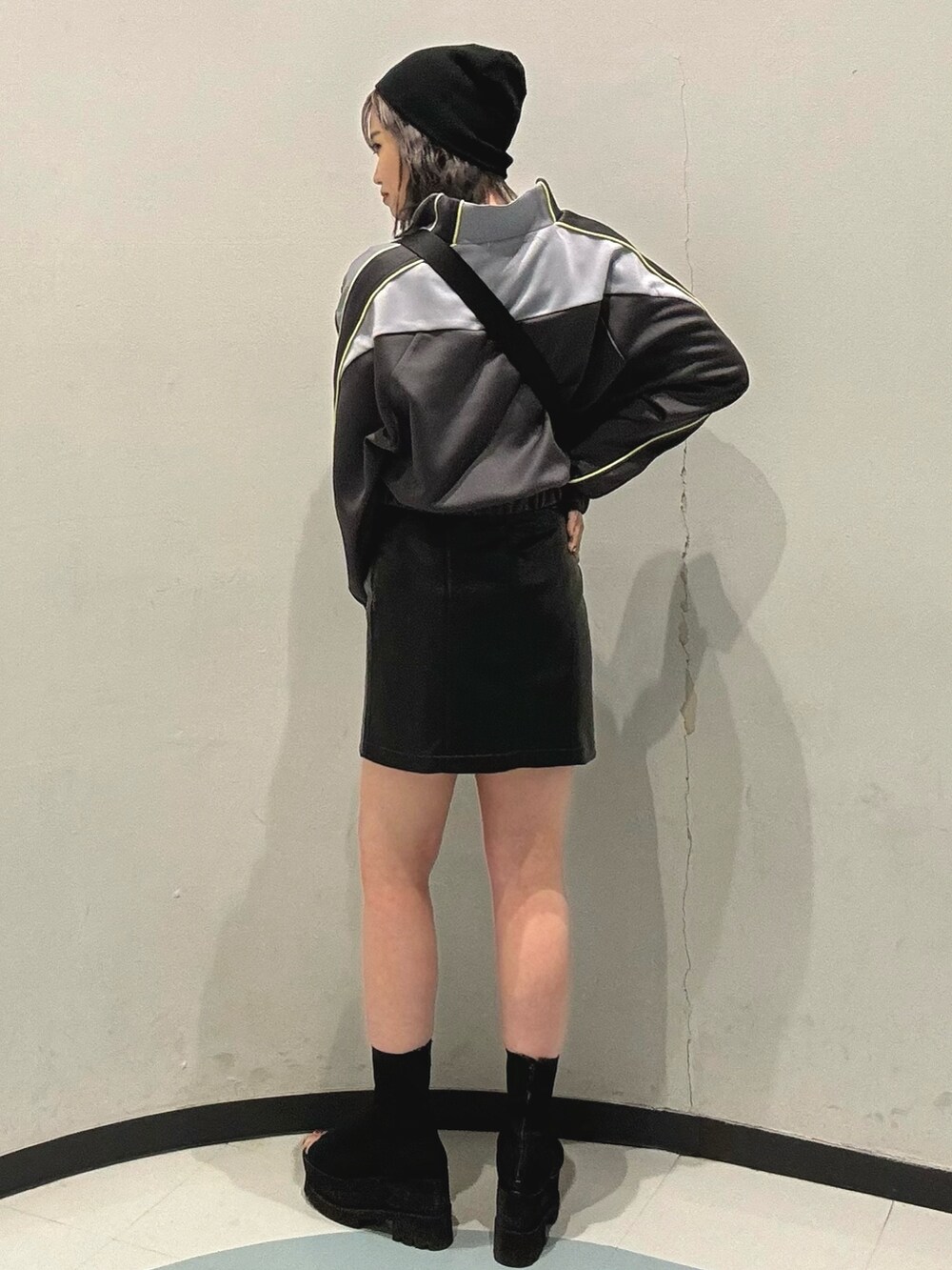 ブラック系のブーツ、グレー系のブルゾン、ブラック系のスカートを着用したレディースの春コーディネートの2枚目の写真