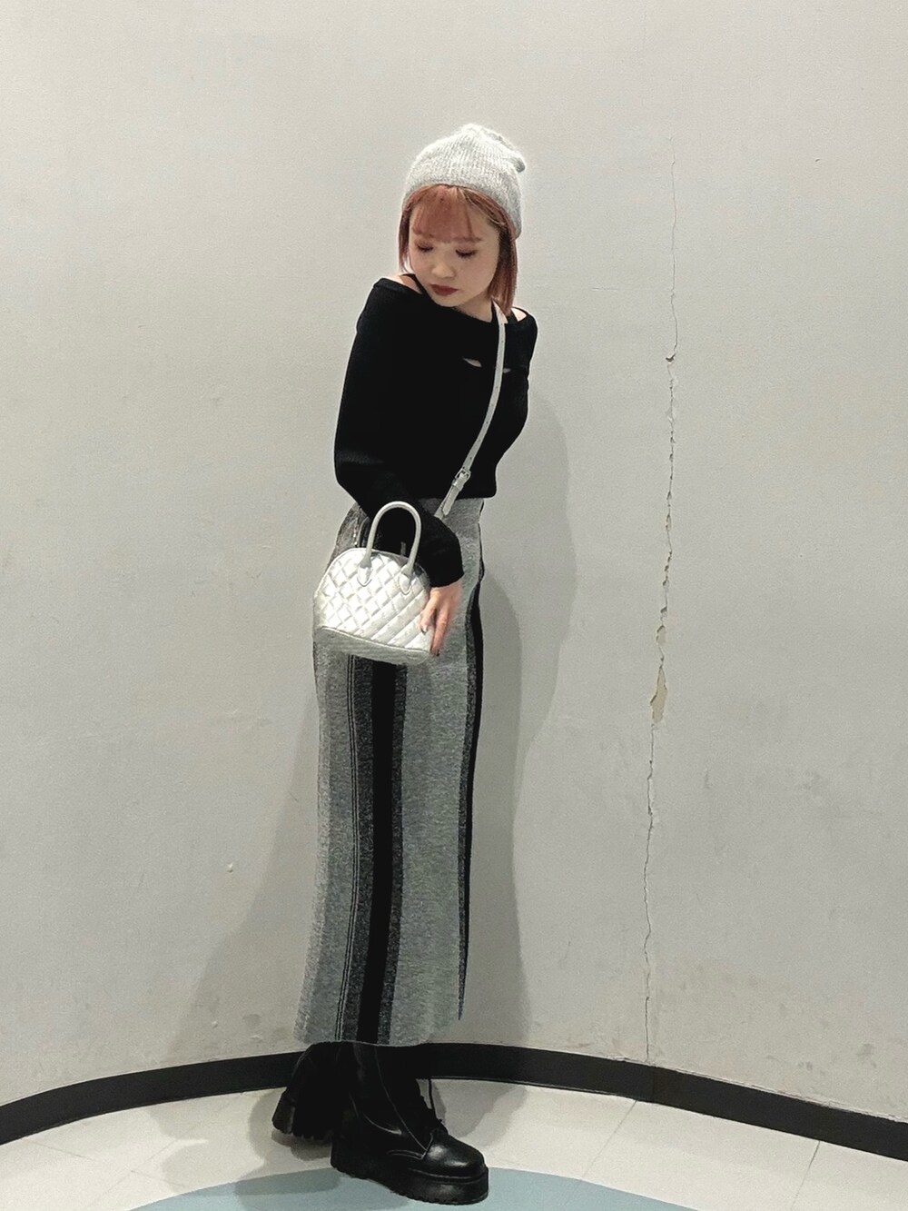 ブラック系のブーツ、シルバー系のハンドバッグ、グレー系のスカートを着用したレディースの冬コーディネートの2枚目の写真