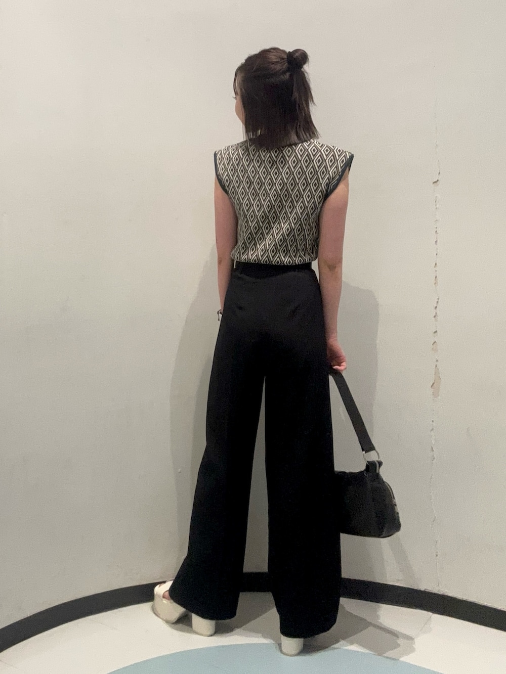 ホワイト系のサンダル、ブラック系のハンドバッグ、グリーン系のタンクトップを着用したレディースの夏コーディネートの3枚目の写真