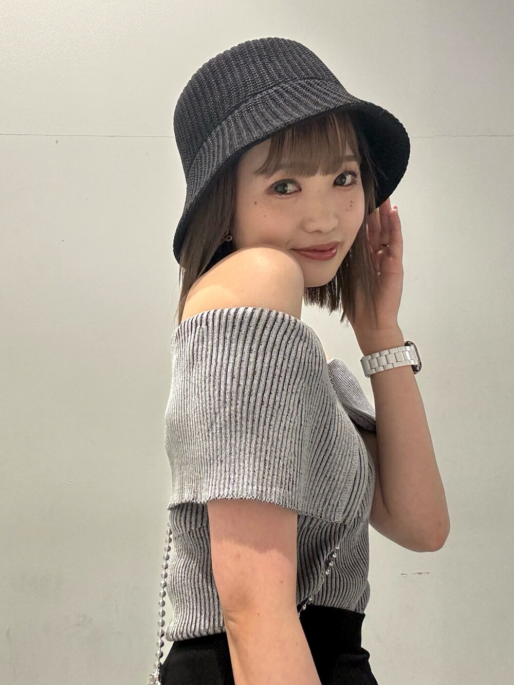 グレー系のニット/セーター、ブラック系のスカート、オレンジ系のショルダーバッグを着用したレディースの春コーディネートの7枚目の写真