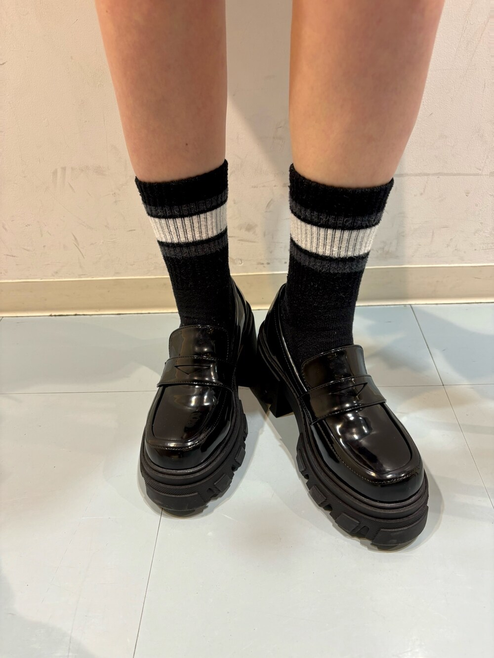 ブラック系のローファー、オレンジ系のニット/セーター、グレー系のワンピースを着用したレディースの春コーディネートの7枚目の写真