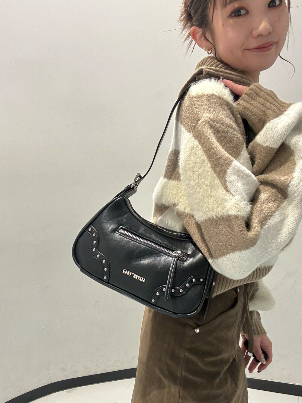 ホワイト系のニット/セーター、ブラウン系のスカート、ブラック系のブーツを着用したレディースの秋コーディネートの5枚目の写真